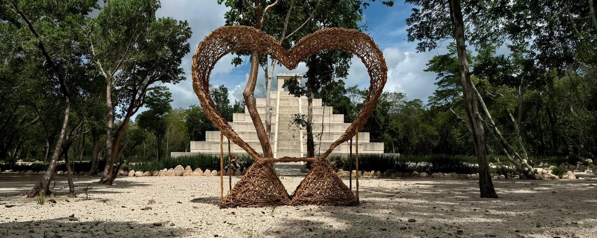 Mukta Residencial — escultura corazón frente a edificio piramidal